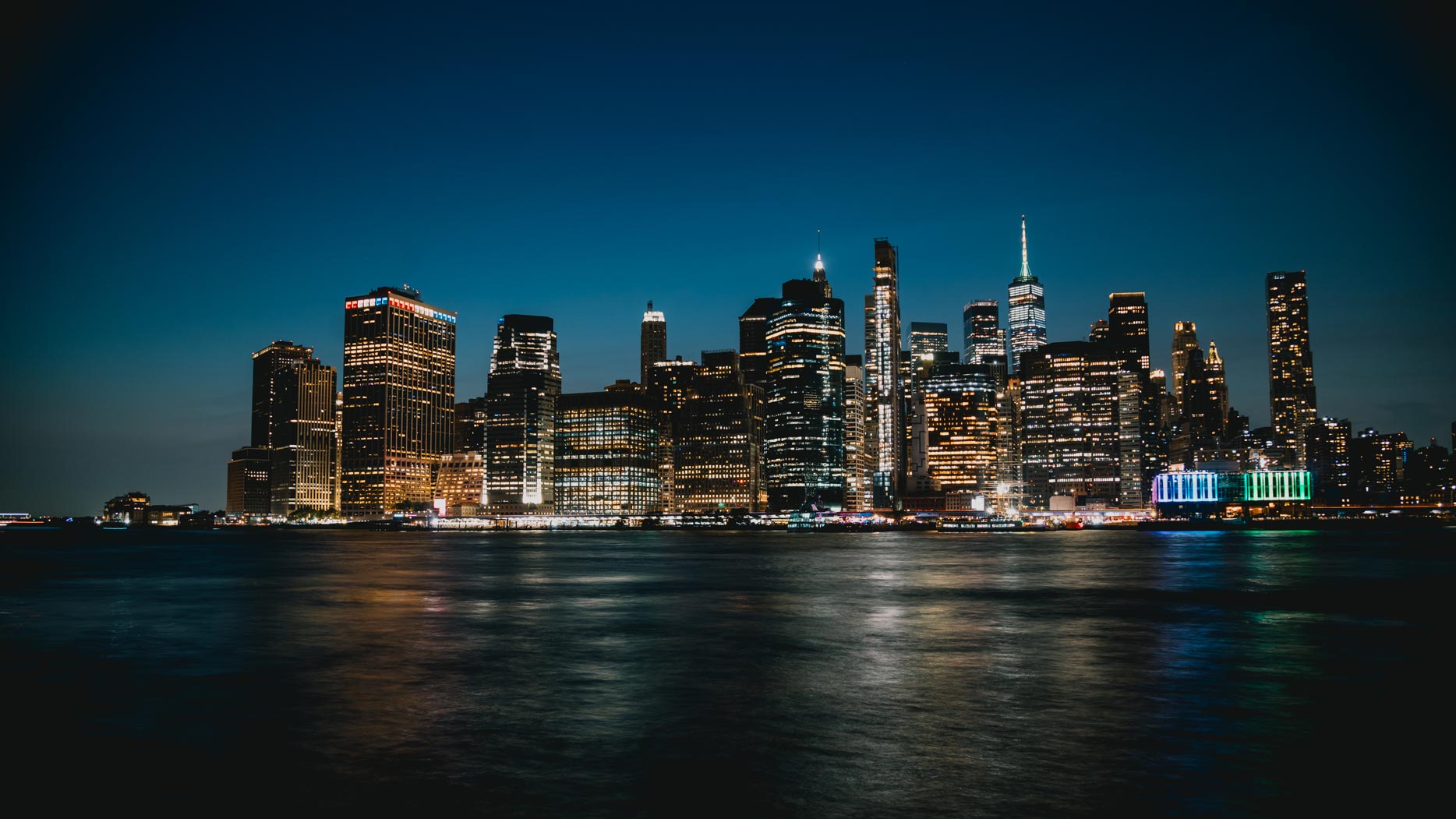 New York City skyline illuminated at night, viewed across the river
